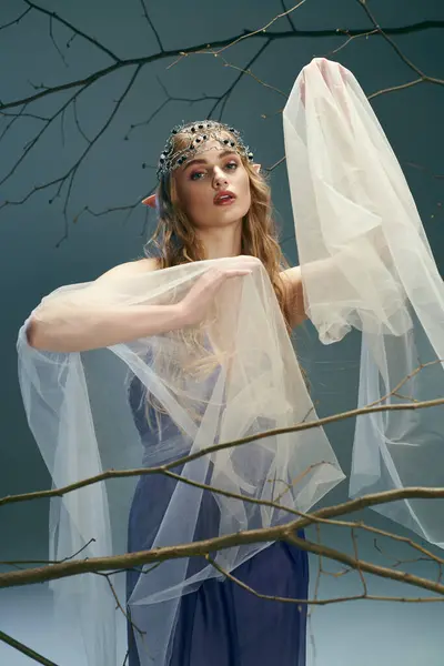A young woman in a beautiful blue dress and a flowing white veil, embodying the essence of a fairy or fantasy elf princess in a studio setting. — Stock Photo