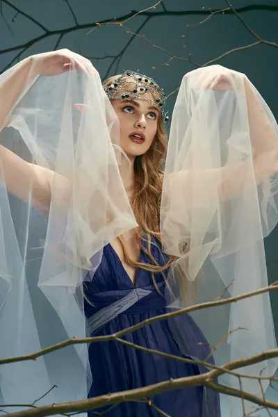 Молодая женщина в синем платье с вуалью над головой, источающая ауру фей и фантазий в студии. — стоковое фото