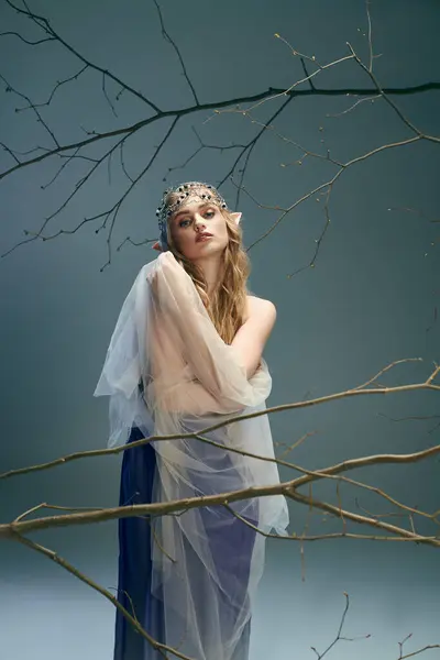 Una joven con un vestido blanco encarna una presencia etérea mientras se levanta con gracia frente a un árbol majestuoso. - foto de stock