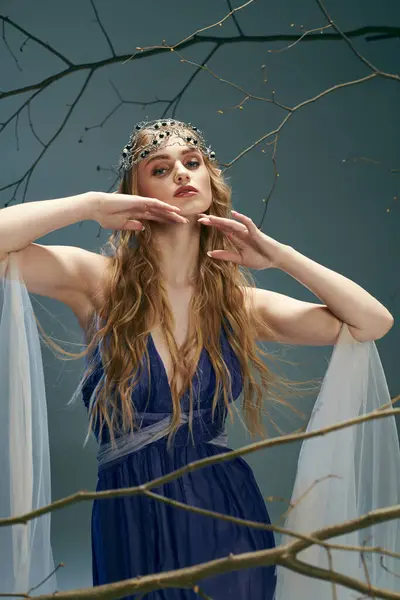 Eine junge Frau in einem blauen Kleid steht anmutig vor einem majestätischen Baum in einem Atelier und verkörpert eine Elfenprinzessin. — Stockfoto