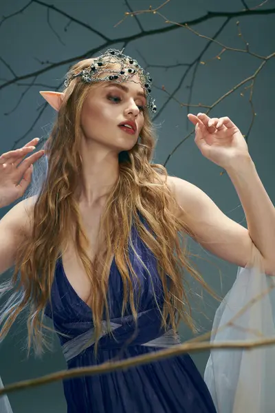Una joven con el pelo largo encarna a una princesa de hadas en un vestido azul, exudando un sentido de la magia y la fantasía. - foto de stock