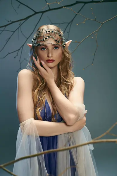 Uma jovem mulher em um vestido azul, adornada com uma coroa, exalando uma presença real e mística em um estúdio. — Fotografia de Stock
