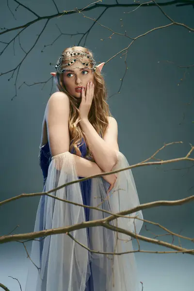 Uma jovem mulher, semelhante a uma princesa duende, faz uma pose em um vestido azul em um estúdio mágico. — Fotografia de Stock