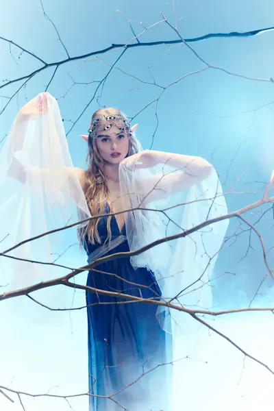 Uma jovem mulher exala magia de fada em um vestido azul e véu branco em um estúdio caprichoso. — Fotografia de Stock