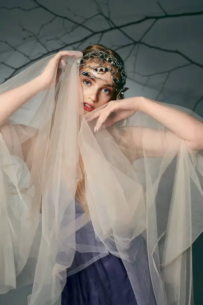 Uma jovem mulher em um vestido com um véu adornando a cabeça parece uma princesa de fadas em um cenário de fantasia. — Fotografia de Stock