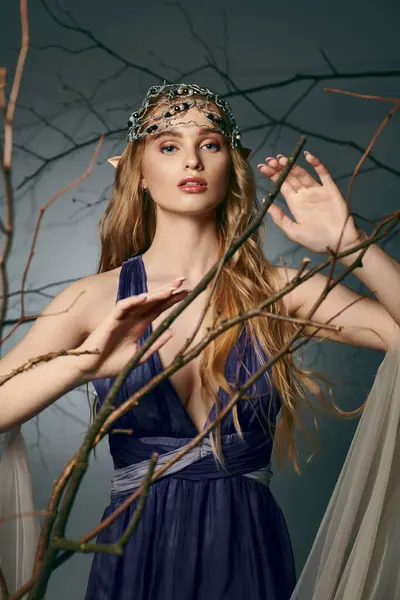 Молодая женщина в синем платье в короне, воплощающая суть феи и фантазии в студийной обстановке. — стоковое фото