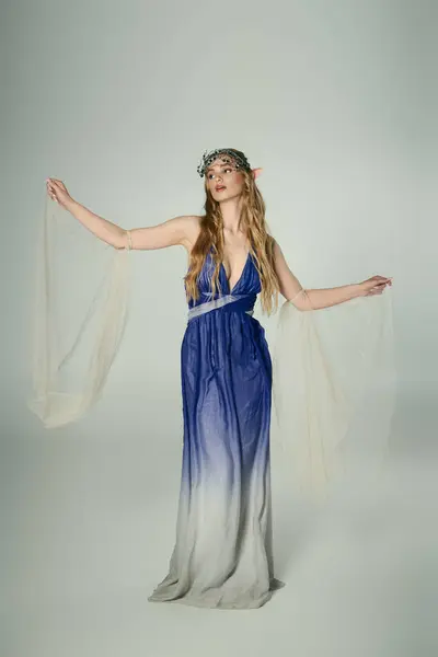 Eine junge Frau in einem blau-weißen Kleid, die das Wesen einer Fee oder Elfenprinzessin in einem verträumten Studio-Setting verkörpert. — Stockfoto