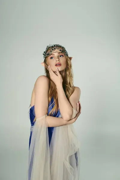 Une jeune femme en robe bleue portant une couronne sur la tête, incarnant l'essence d'une princesse féerique magique dans un décor de studio. — Photo de stock