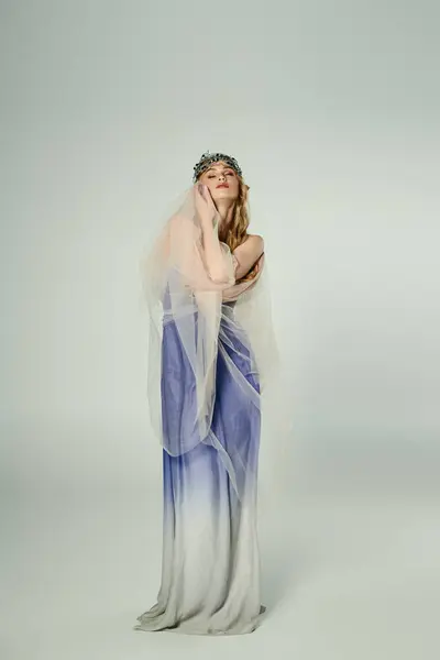 Uma jovem mulher vestida com um vestido azul e branco com um véu fluente, incorporando a essência de uma princesa de fadas em um estúdio. — Fotografia de Stock