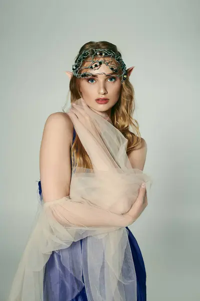 Молодая женщина, украшенная вуалем и головным убором, воплощающая сказку с очаровательной студийной обстановкой. — стоковое фото