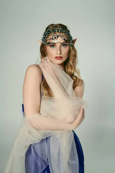 Uma jovem mulher adornada em um véu e headpiece, incorporando uma fantasia de fada com um estúdio encantador. — Fotografia de Stock