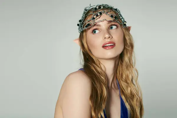 Uma jovem mulher usando uma coroa, incorporando uma princesa elfo-como fada em um estúdio caprichoso. — Fotografia de Stock