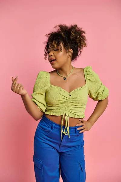 Стильна афроамериканська жінка позує в яскраво-жовтих верхніх і синіх штанях. — стокове фото