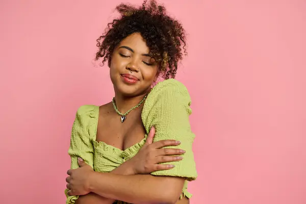 Uma mulher afro-americana emocional bonita em um top amarelo elegante abraçando seus braços. — Fotografia de Stock