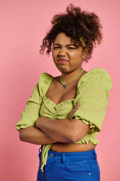 Elegante mujer afroamericana con los brazos cruzados frente al vibrante telón de fondo rosa. — Stock Photo