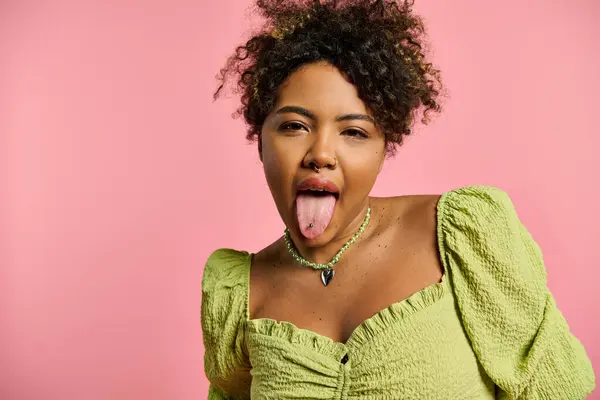 Uma mulher afro-americana vibrante e elegante puxa um rosto engraçado com a língua para fora. — Fotografia de Stock