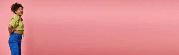 Stylish African American woman striking a pose in front of a vibrant pink wall. — Stock Photo