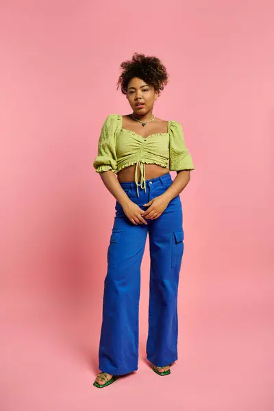 A beautiful African American woman in stylish attire poses gracefully against a vibrant pink backdrop. — Stock Photo