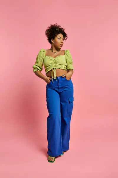 African American woman in stylish attire posing against vibrant pink backdrop. — Stock Photo