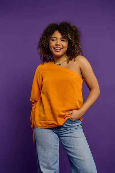 Stylish woman posing against vibrant backdrop in orange top. — Stock Photo