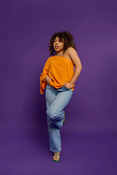 Stylish African American woman poses in vibrant orange top against colorful backdrop. — Stock Photo