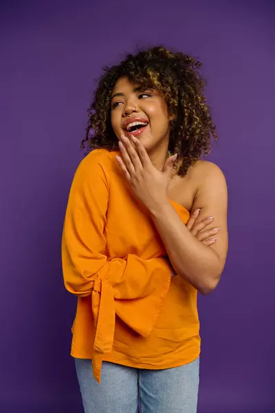 African American woman standing with hands on chest in stylish attire against vibrant backdrop. — Stock Photo