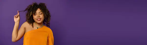 Stylish African American woman in orange top posing actively. — Stock Photo