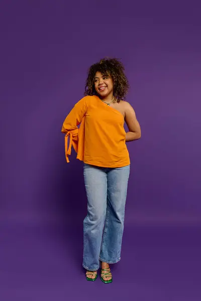 Una mujer afroamericana con estilo posa frente a un vibrante fondo púrpura. - foto de stock