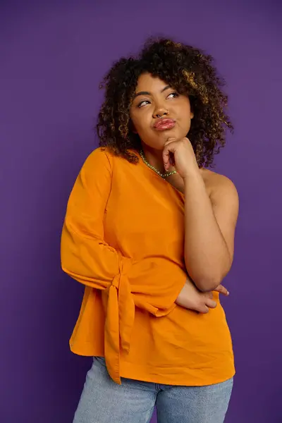 Mulher afro-americana elegante na camisa laranja coloca confiantemente contra o cenário vibrante. — Fotografia de Stock