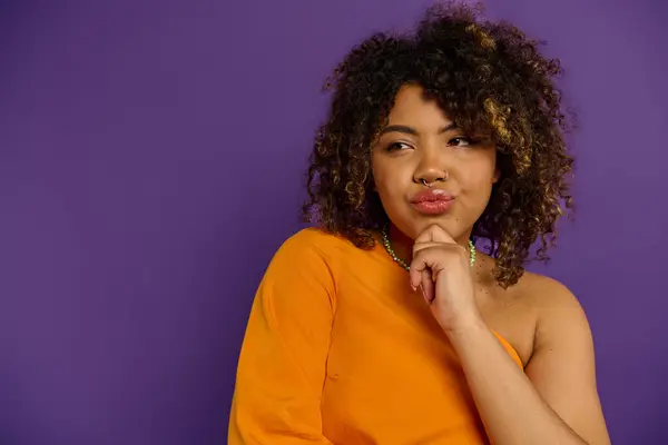 Stylish African American woman with curly hair poses against vibrant backdrop. — Stock Photo