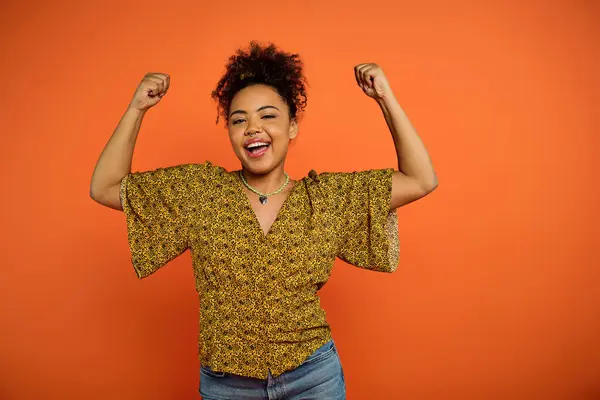 Stylish African American woman joyfully raising arms in vibrant setting. — Stock Photo