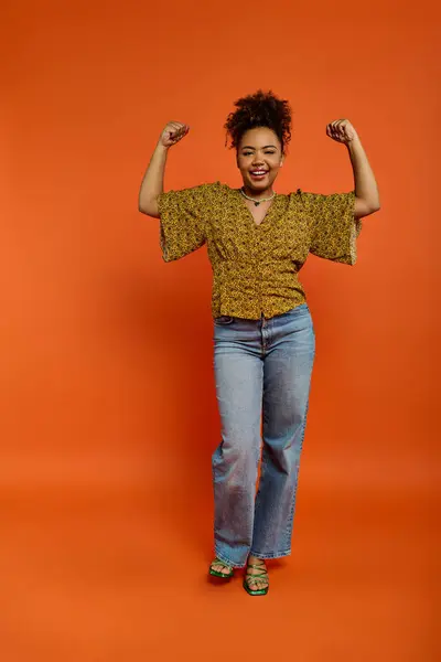 Mulher afro-americana elegante posa contra um cenário laranja vibrante. — Fotografia de Stock