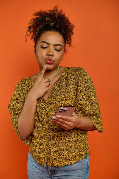 Une belle femme afro-américaine en tenue élégante regarde son téléphone portable. — Photo de stock