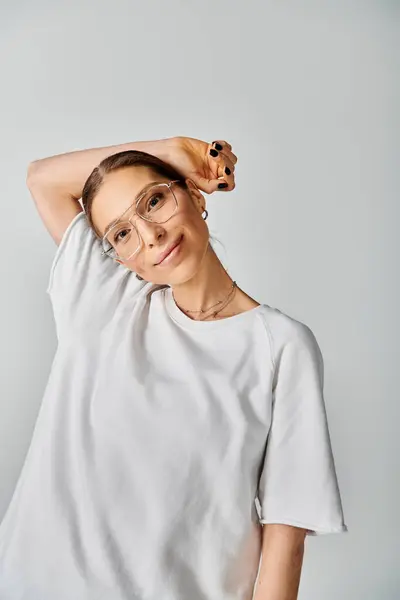 Una joven con una camisa blanca y gafas sobre un fondo gris, exudando elegancia y estilo — Stock Photo