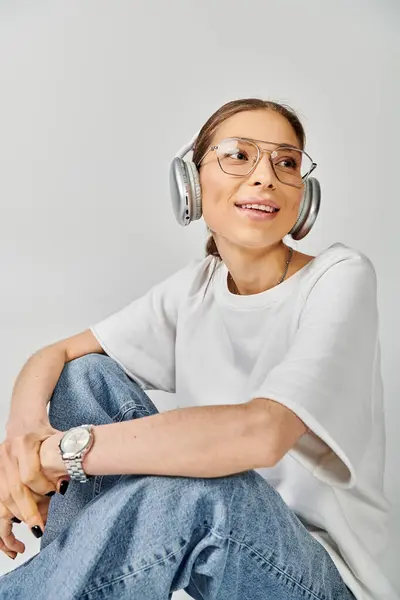 Eine junge Frau in weißem T-Shirt und Brille mit Kopfhörern, verloren in der Musik. — Stock Photo