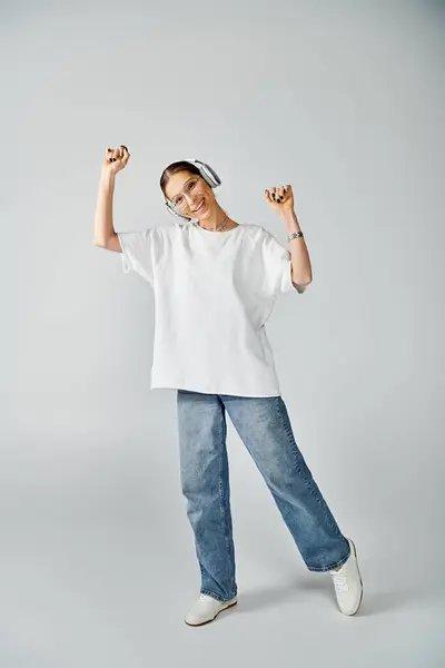 Eine stylische junge Frau in weißem Hemd und Jeans posiert vor neutralem grauen Hintergrund. — Stockfoto