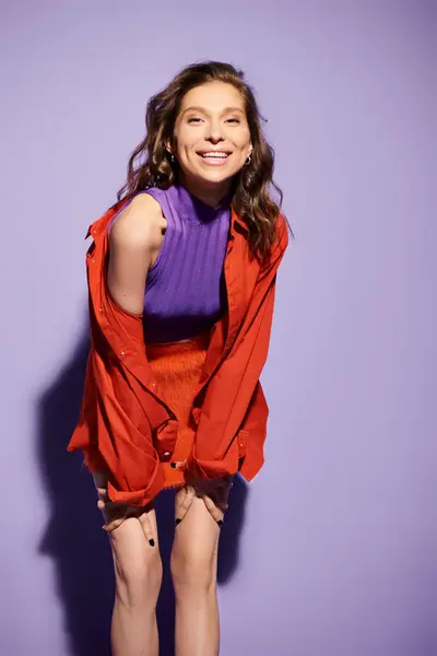 Une jeune femme élégante respire l'élégance et la confiance alors qu'elle pose pour une photo dans un rouge vif sur un fond violet. — Photo de stock