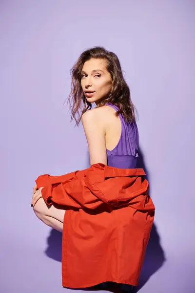 Une jeune femme élégante dans un haut violet et jupe rouge pose sur un fond violet vibrant. — Photo de stock