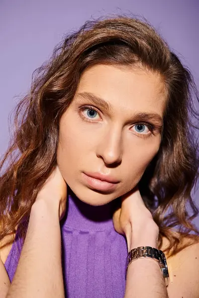 A stylish young woman in a purple shirt striking a pose against a vibrant purple background. — Stock Photo