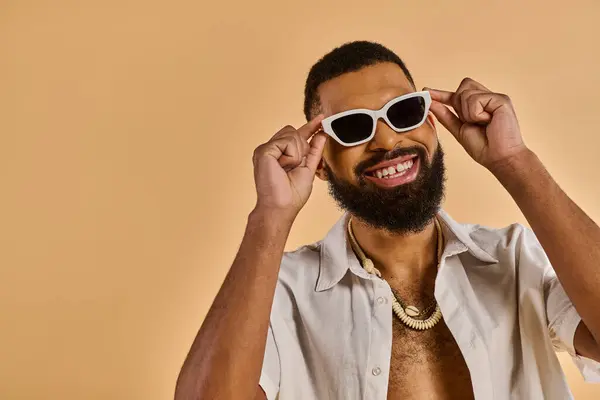 Un hombre con una barba elegante y gafas de sol de moda emana confianza y carisma mientras posa para la cámara. - foto de stock