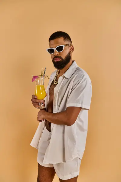 Un homme en chemise blanche croquante tient délicatement un verre de jus d'orange frais, mettant en valeur un moment de tranquillité et de rafraîchissement. — Photo de stock