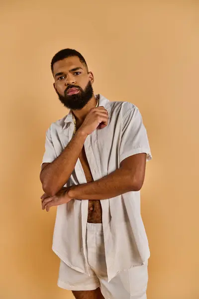 Um homem com uma barba cheia vestindo uma camisa branca nítida olha com confiança para a câmera, exalando elegância e masculinidade. — Fotografia de Stock