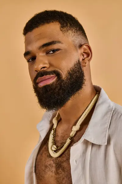 A man exudes an air of mystery, the focus on his striking beard and intricate necklace, evoking a sense of ancient wisdom and strength. — Stock Photo