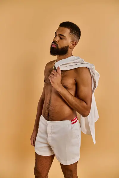 Un hombre con la barba llena está sin camisa en un entorno tranquilo, conectándose con la naturaleza a través de su pecho desnudo. - foto de stock