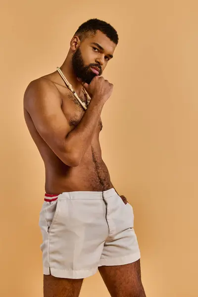 Ein Mann mit Vollbart posiert selbstbewusst vor der Kamera und zeigt seinen Körperbau ohne Hemd. Er strahlt Stärke und Männlichkeit aus. — Stockfoto