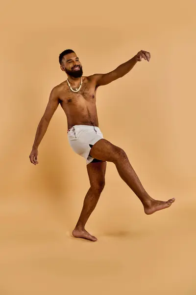 Ein hemdloser Mann mit Bart tanzt fröhlich in der riesigen Wüste und bewegt sich im unsichtbaren Takt, wobei seine nackten Füße Staub aufwirbeln. — Stockfoto