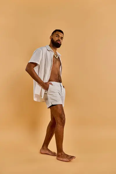 A man with a beard standing shirtless in front of a tan background, exuding a sense of freedom and connection to the earth. — Stock Photo