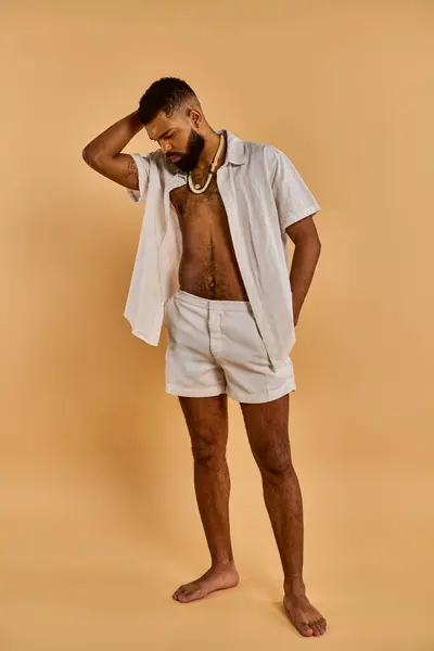 Un uomo senza maglietta si trova fiduciosamente davanti a uno sfondo caldo e abbronzato, trasudando forza e vitalità nella luce dorata. — Foto stock