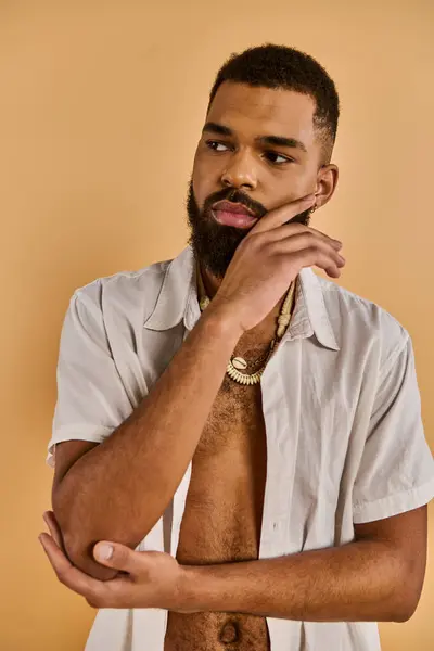 Um homem barbudo sem camisa golpeia uma pose confiante, exalando masculinidade e força enquanto olha para a distância. — Fotografia de Stock
