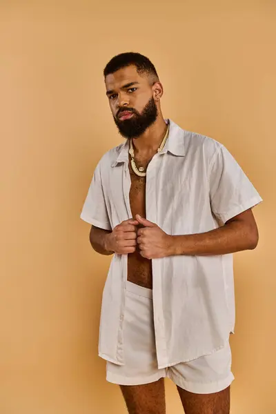 Стильний чоловік з бородою випадково одягнений у білу сорочку і шорти, виключаючи розслаблений і відкинутий вібе. — стокове фото